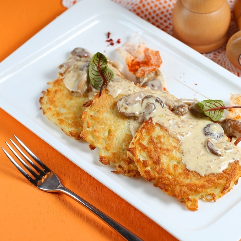 Золотистые дранники с беконом и соусом из белых грибов